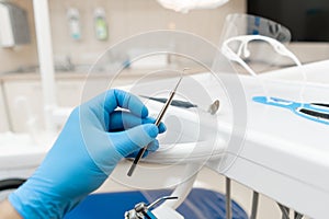 The hand of the dentist in the glove holds tool probe. . Stomatological instrument in the dentist clinic. Dental work in