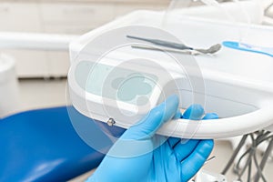 The hand of the dentist in the glove presses the control buttons of the chair.. Dental work in clinic. Operation, tooth