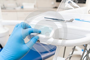 The hand of the dentist in the glove presses the control buttons of the chair.. Dental work in clinic. Operation, tooth