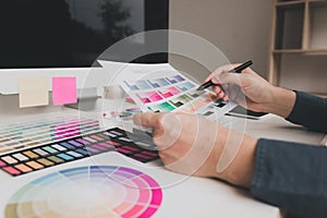 Hand designer choosing colors for doing graphic on laptop