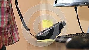 Hand dialing number on office phone with sticky note messages