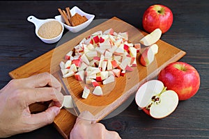 Hand dicing fresh apples on cutting board for making apple compote photo