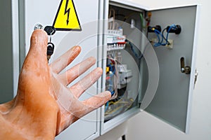 Hand in a dielectric glove on a background of an electrical panel photo