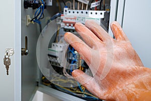 A hand in a dielectric glove opens the door to the electrical panel photo