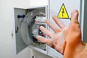 A hand in a dielectric glove reaches for the electrical panel photo