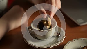 Hand dip cookie in cup of coffee