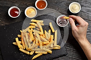 Hand dipping french fries in sauce