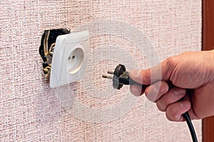 Hand disconnects or connects the plug to a broken outlet, risk of electric shock