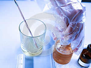 Hand discovers hazardous chemicals. A chemist mixes a yellowish substance. Work in the laboratory