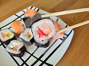 Hand with disposable chopsticks holds sake nigiri sushi with salmon photo