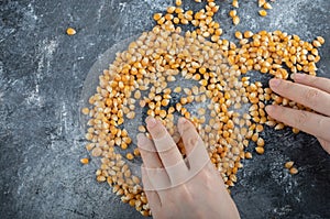 Hand distributing uncooked popcorn seeds on a marble background