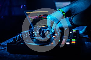 Hand DJ mixing electronic music on a professional controller