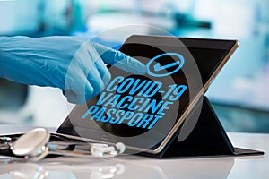 Hand of a doctor pressing a button on the tablet that authorizes the Covid-19 digital vaccination passport for a traveling patient photo