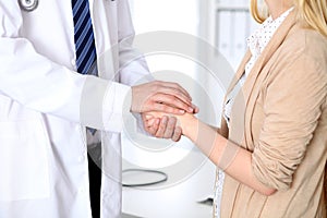 Hand of doctor reassuring her female patient. Medical ethics and trust concept