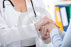 Hand of doctor reassuring her female patient. Medical ethics and trust concept. Handshake, hands closeup