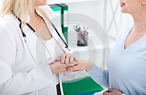 Hand of doctor reassuring her female patient. Medical ethics and trust concept. Handshake, hands closeup