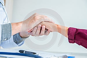 Hand of doctor reassuring to male patient doctor at the clinic giving a handshake to the patient, health care concept