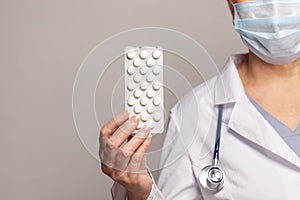 Hand of doctors holding pills on light blue background