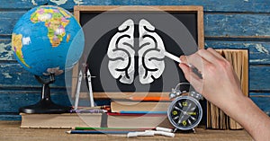 Hand drawing brain on blackboard with study objects