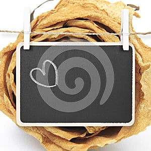 Hand drawing heart on blackboard with dry white rose background, included clipping path