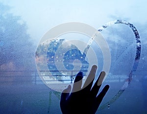 Hand drawing heart on wet window