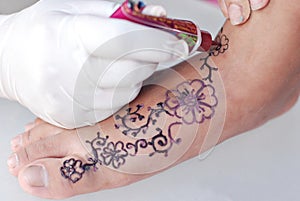 Hand drawing henna art on a foot with white background