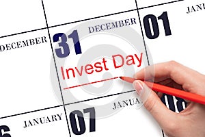 Hand drawing red line and writing the text Invest Day on calendar date December 31. Business and financial concept.