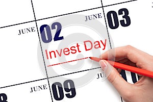 Hand drawing red line and writing the text Invest Day on calendar date June 2. Business and financial concept.