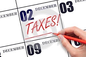 Hand drawing red line and writing the text Taxes on calendar date December 2. Remind date of tax payment