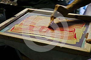 Hand drawing squeegee over inked silk screen