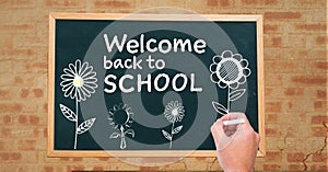 Hand drawing Welcome back to school text and flowers on blackboard