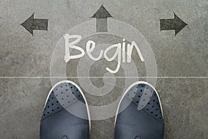 Hand drawn BEGIN design word on front of business man feet