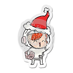 hand drawn distressed sticker cartoon of a happy spacegirl holding moon rock wearing santa hat