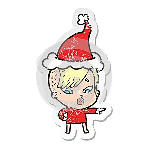 hand drawn distressed sticker cartoon of a surprised girl pointing wearing santa hat