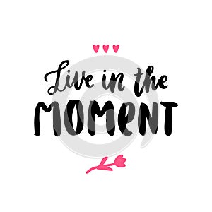 Hand-drawn lettering phrase: Live in the moment, of black ink on a white background.