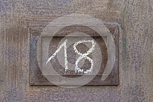 Hand drawn number eighteen on weathered metal doorway