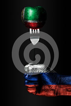 A hand with a drawn Russia flag holds a fork, on which is a ball with a drawn Chechnya flag, a sign of influence, pressure, grip