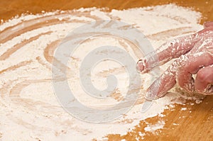 Hand draws heart on a flour