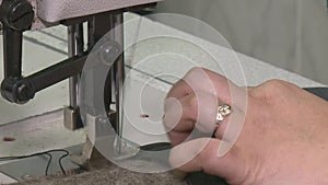 Hand of a dressmaker supporting a cloth while sewing on a machine