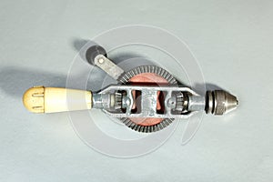 Hand drill with yellow handle on a gray background