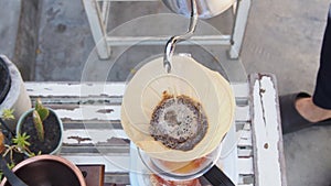 Hand drip coffee, barista pouring hot water over roasted grinded coffee powder making drip brew coffee