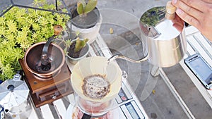 Hand drip coffee, barista pouring hot water over roasted grinded coffee powder making drip brew coffee