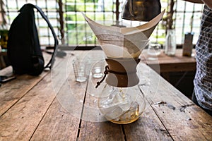 Hand drip coffee, Barista pouring water on coffee ground with filter on wooden table, vintage style