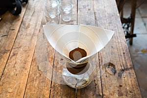 Hand drip coffee, coffee ground with filter on wooden table, vintage style