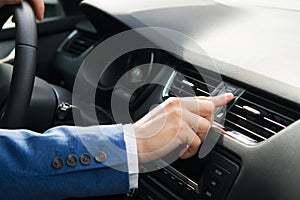 The hand of the driver of the car opens the air intake on the car