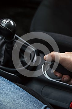 Hand of driver on handbrake lever and manual transmission lever in sight