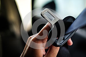 Hand of driver holding seat belt safety belt lock in car.