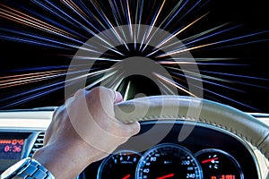 Hand of driver holding steering wheel with abstract speed motion light lines background