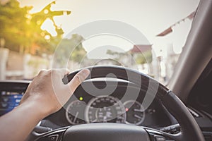 Hand of driver on steering wheel of car