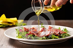 hand drizzling olive oil over a salami salad